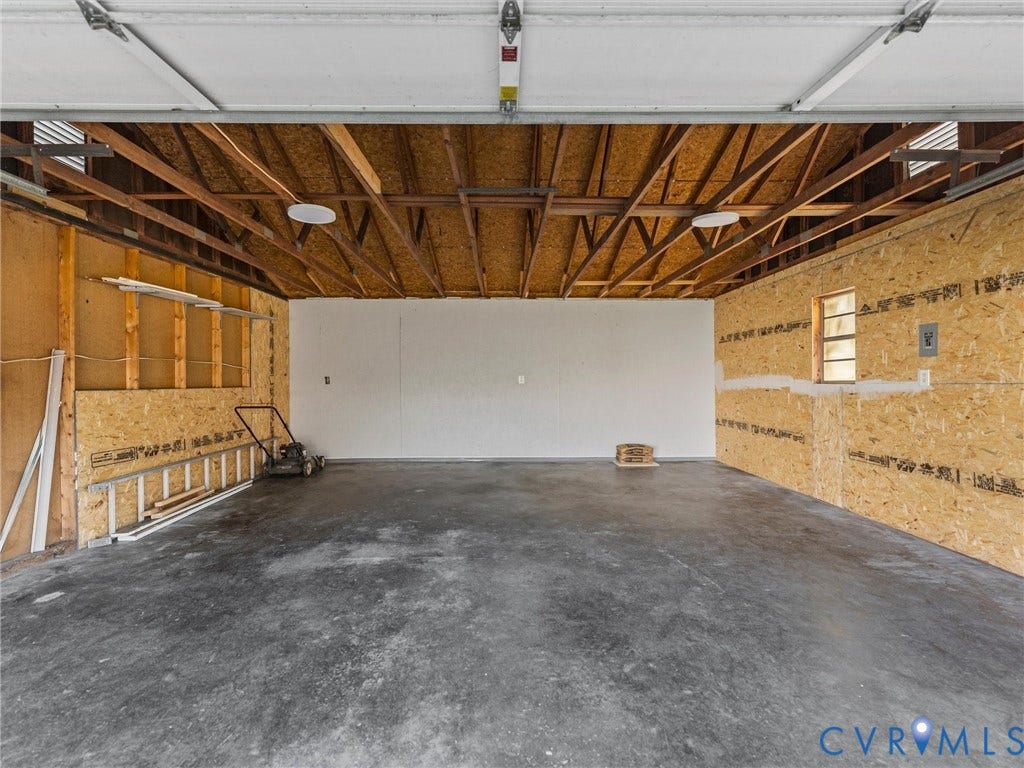 3303 Jowin Lane, Henrico, VA 23223 Attached garage featuring concrete flooring, exposed wood-truss ceiling, and oriented strand board wall paneling