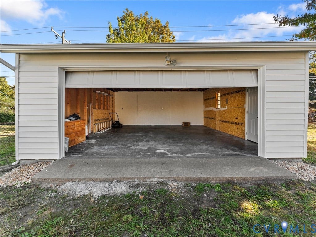 3303 Jowin Lane, Henrico, VA 23223 Detached garage featuring white horizontal siding, a concrete floor, a wide roll-up door, and a separate side entry door