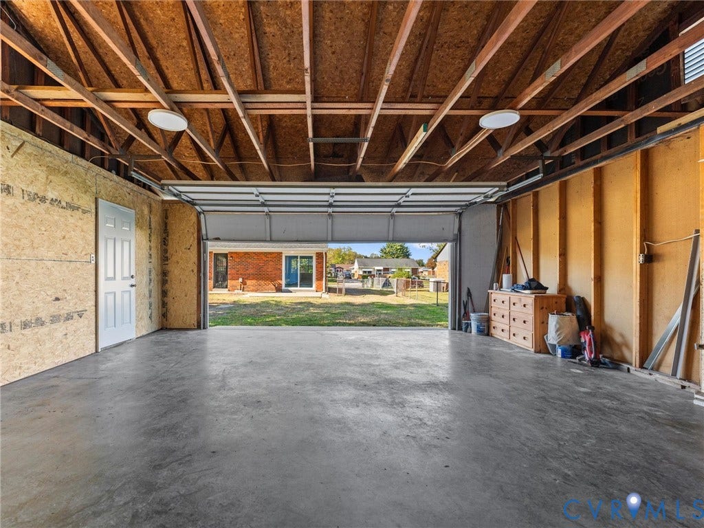 3303 Jowin Lane, Henrico, VA 23223 Detached garage featuring exposed wood framing, concrete flooring, overhead lighting, and a single pedestrian entry door