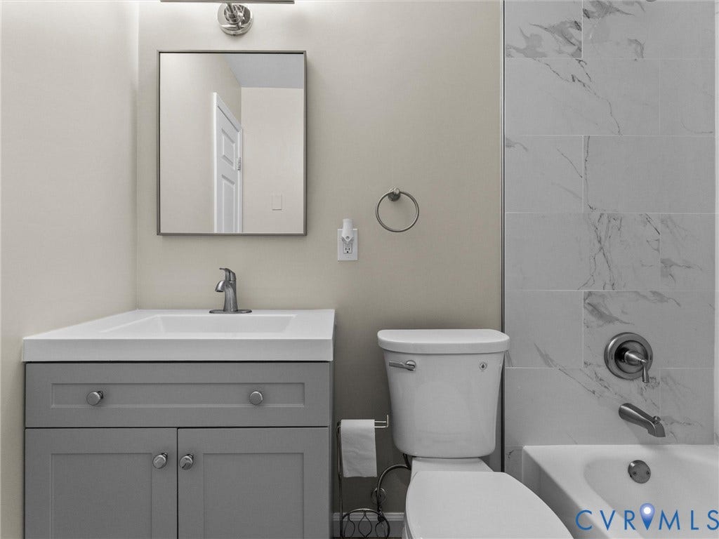 3303 Jowin Lane, Henrico, VA 23223 Grey vanity with a white countertop and rectangular sink, square mirror, chrome faucet, and tile surround bathtub