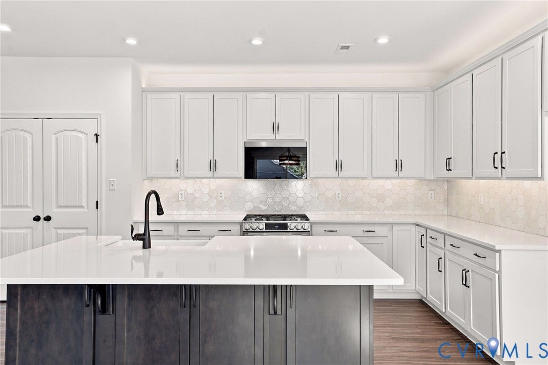 7712 Hawthorne Avenue, Henrico, VA 23227 Kitchen featuring white shaker cabinetry, an expansive center island with a dark-toned base, stone-style countertops, a honeycomb-patterned tile backsplash, and a matte black gooseneck faucet
