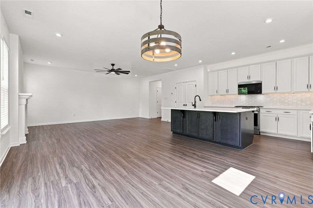 7712 Hawthorne Avenue, Henrico, VA 23227 Kitchen featuring a dark-toned central island with a white countertop, shaker-style white cabinetry, wood-finish flooring, a metal drum pendant light, and recessed lighting