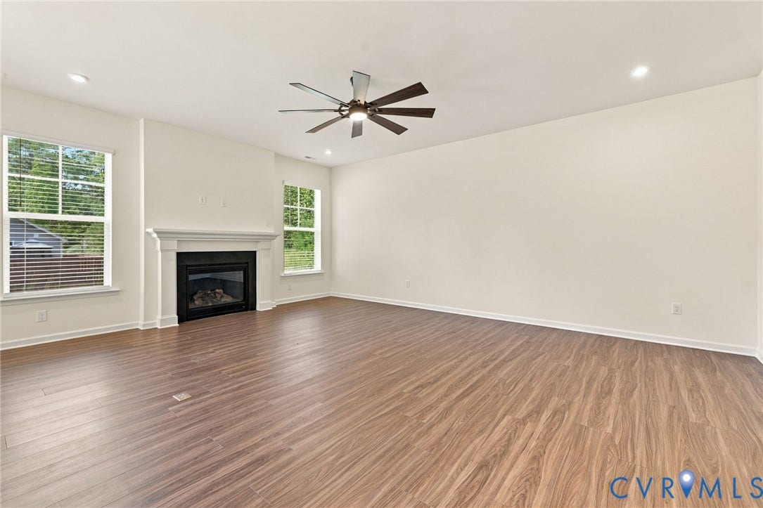 7712 Hawthorne Avenue, Henrico, VA 23227 Wood-finish flooring, fireplace with a decorative mantel, ceiling fan, and large windows with horizontal blinds