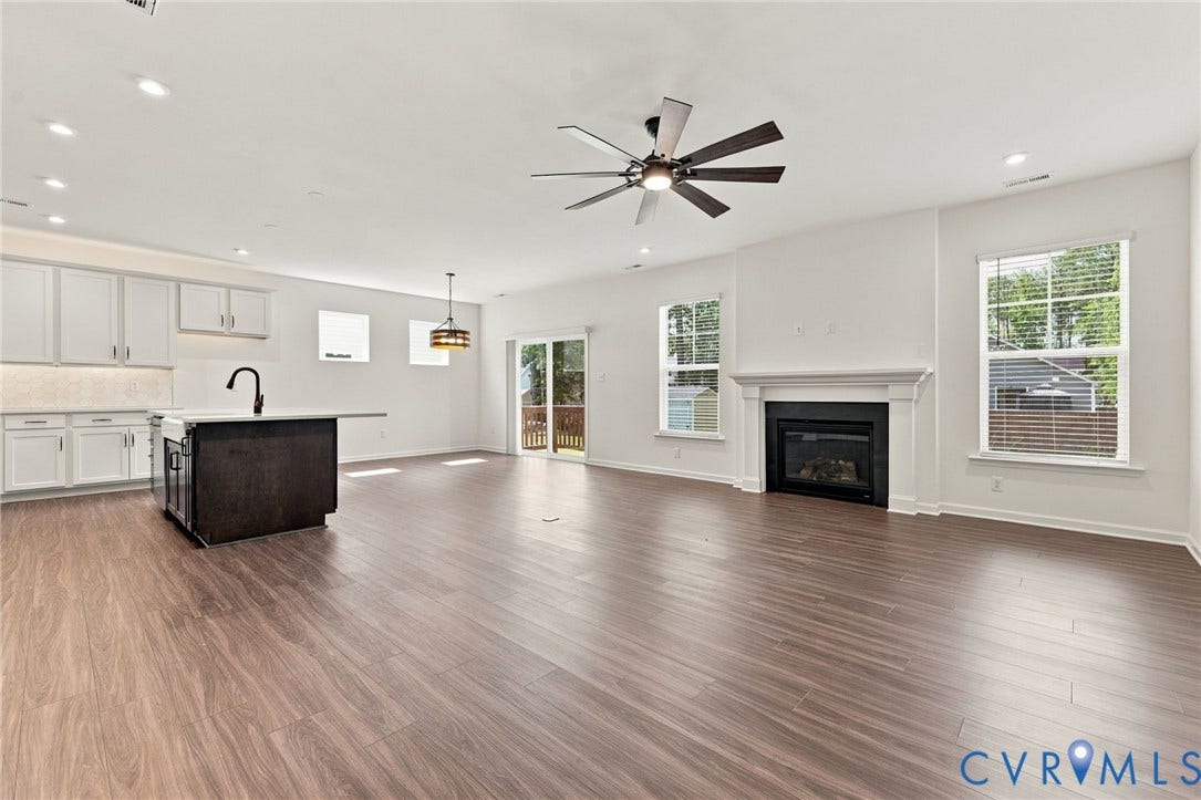 7712 Hawthorne Avenue, Henrico, VA 23227 Open-concept interior featuring wood-finish flooring, a kitchen island with dark cabinetry, recessed lighting, a fireplace with a white mantel, and a ceiling fan