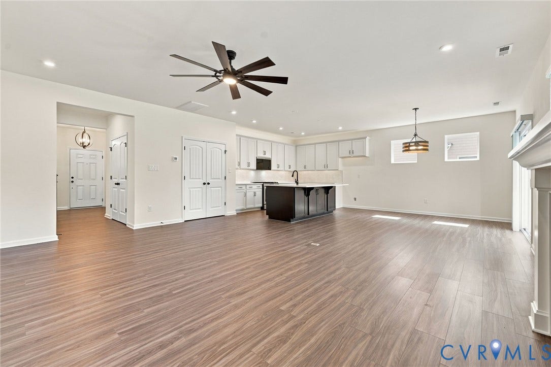7712 Hawthorne Avenue, Henrico, VA 23227 Open-concept kitchen and living area featuring wood-finish flooring, a center kitchen island with dark cabinetry, white perimeter cabinetry, recessed lighting, and a multi-blade ceiling fan