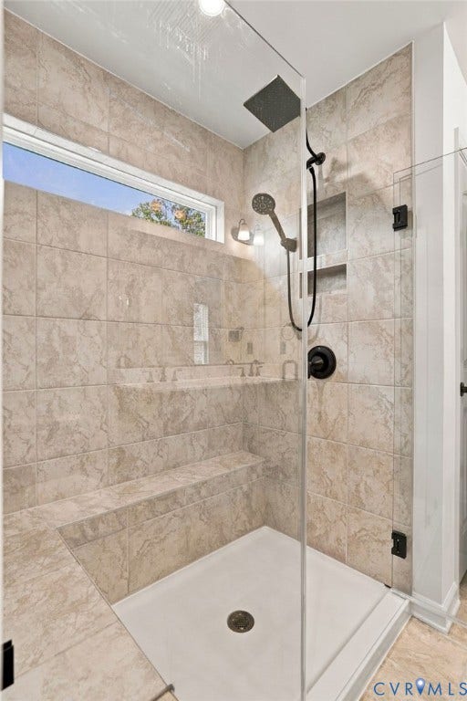 7712 Hawthorne Avenue, Henrico, VA 23227 Walk-in shower featuring floor-to-ceiling tile, frameless glass enclosure, built-in bench seating, integrated wall niche, and rainfall showerhead with matte black finish hardware