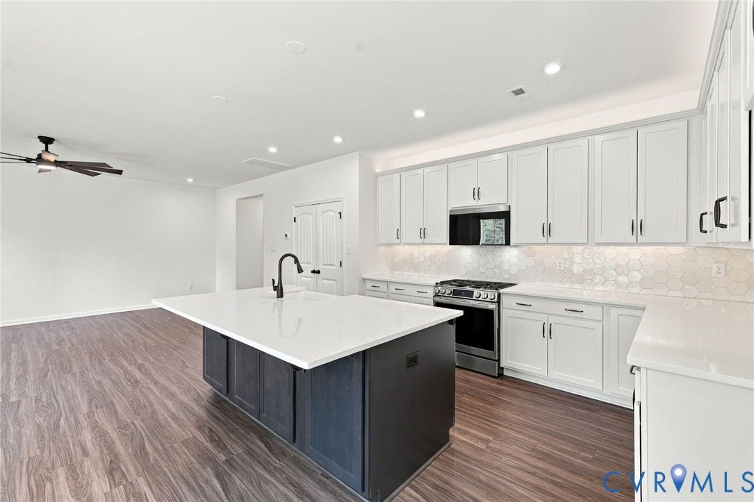 7712 Hawthorne Avenue, Henrico, VA 23227 Kitchen featuring white cabinetry, a contrasting dark island, stone-finish countertops, geometric tile backsplash, and wood-finish flooring
