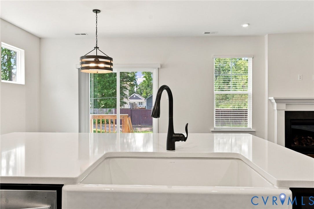 7712 Hawthorne Avenue, Henrico, VA 23227 Kitchen island featuring a white countertop, farmhouse-style sink, matte black gooseneck faucet, drum-style pendant light, and sliding glass door access
