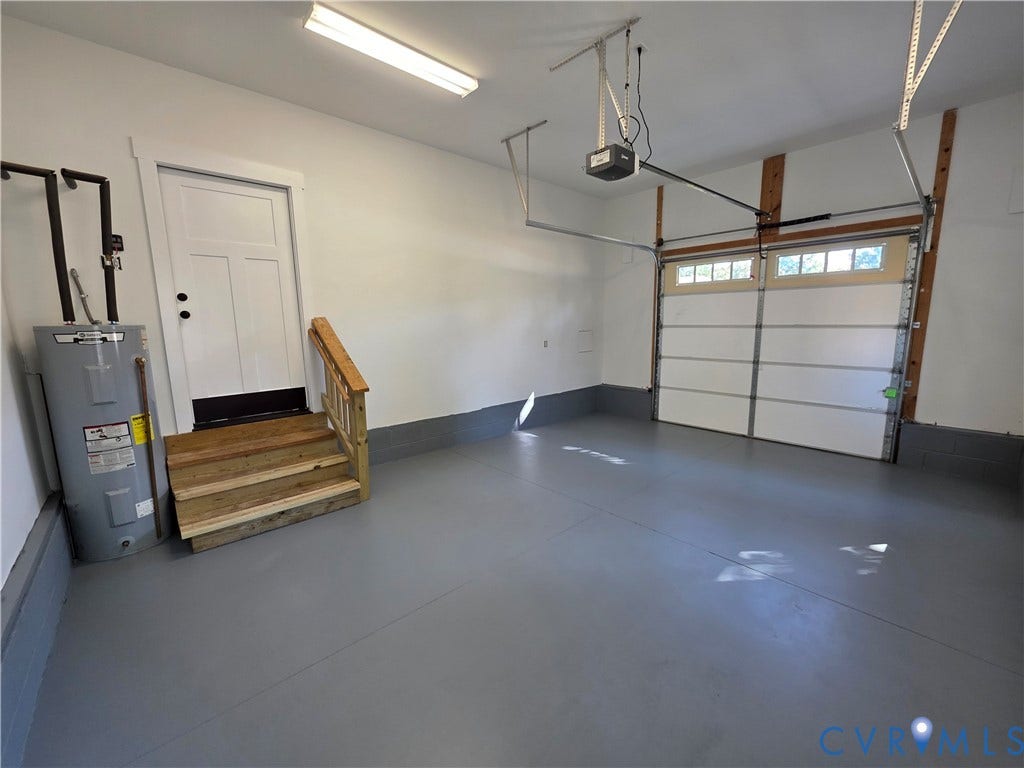 3005 Portsmouth Street, Hopewell, VA 23860 Attached two-car garage featuring a grey epoxy-coated floor, automatic sectional door with glass inserts, white paneled entry door, and wood-finish stair treads with railing