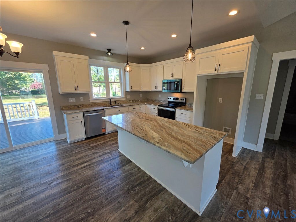 3005 Portsmouth Street, Hopewell, VA 23860 Kitchen featuring white shaker-style cabinetry, natural stone countertops, a central island with an extended breakfast bar, wood-finish flooring, and pendant lighting