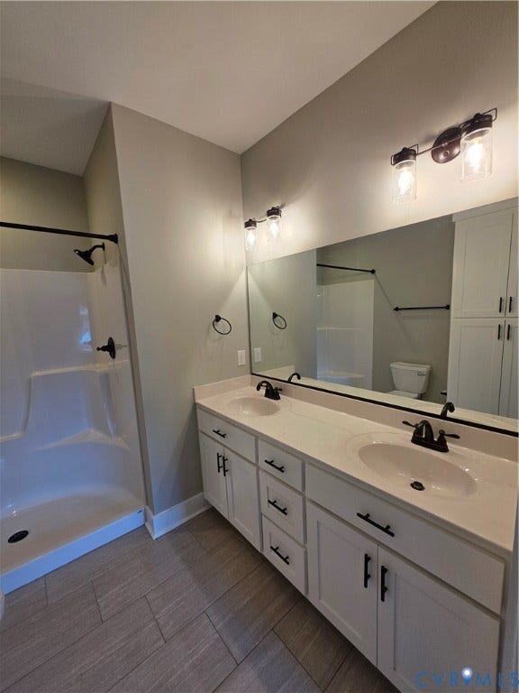 3005 Portsmouth Street, Hopewell, VA 23860 Dual-sink vanity with white cabinetry, integrated solid-surface countertop, matte black fixtures, full-width wall mirror, and porcelain tile flooring