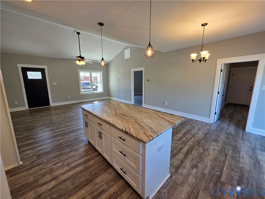 3005 Portsmouth Street, Hopewell, VA 23860 Kitchen island featuring stone countertop, white shaker-style cabinetry, and matte black hardware, complemented by wood-finish flooring and vaulted ceilings