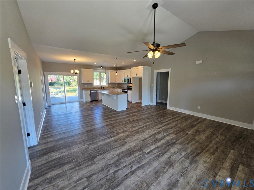 3005 Portsmouth Street, Hopewell, VA 23860 Open-concept interior featuring vaulted ceilings, wood-finish flooring, a kitchen island with stone-surface countertop, white cabinetry, and sliding glass doors