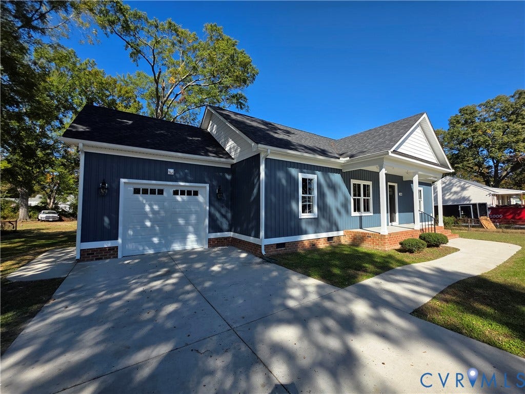 3005 Portsmouth Street, Hopewell, VA 23860 Dark-toned vertical siding exterior featuring a covered front porch, brick foundation detailing, multi-paned windows, and an attached garage with a concrete driveway