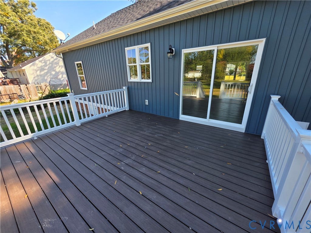 3005 Portsmouth Street, Hopewell, VA 23860 Raised deck featuring dark composite decking, white baluster railings, vertical dark-toned exterior siding, and a sliding glass door