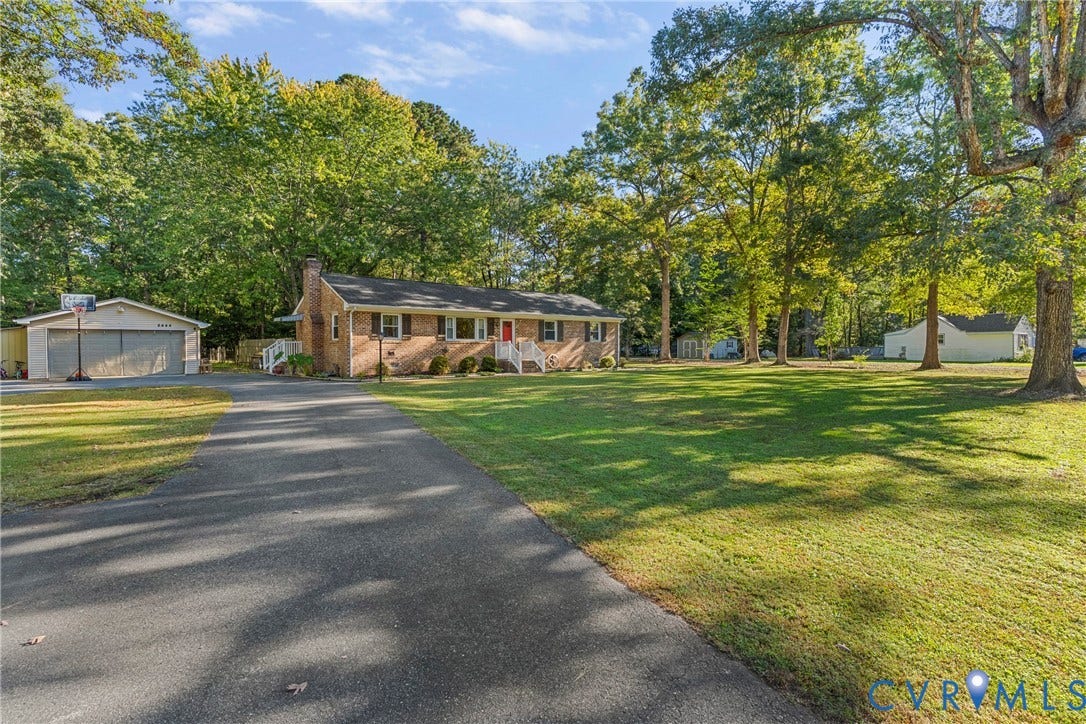 8444 New London Road, Mechanicsville, VA 23116 Brick exterior residence featuring a sprawling lawn, paved driveway, detached two-car garage, and mature trees