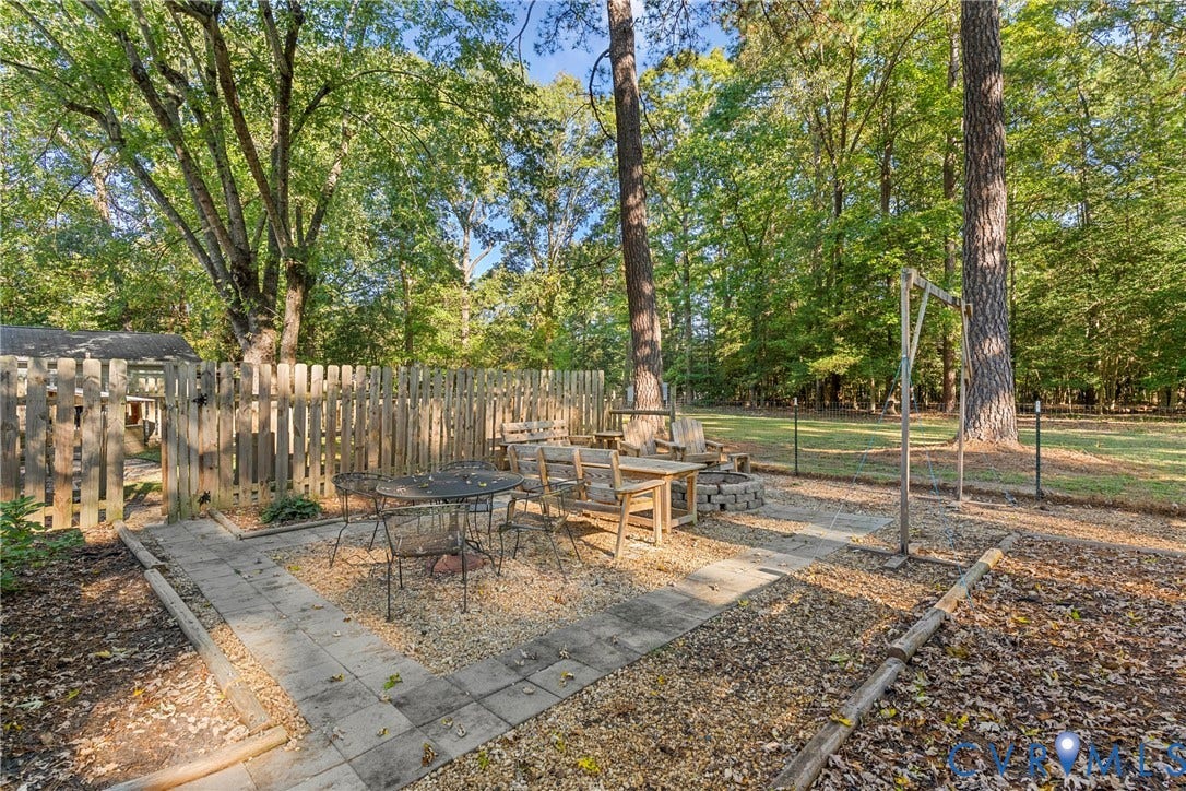 8444 New London Road, Mechanicsville, VA 23116 Outdoor living area featuring a paved stone patio, gravel base, stone-encased fire pit, and wood-slat privacy fencing