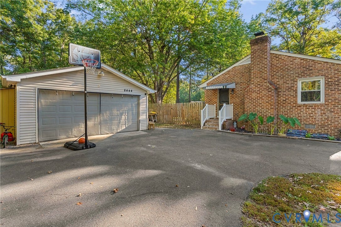 8444 New London Road, Mechanicsville, VA 23116 Brick exterior with a prominent chimney, detached garage, asphalt driveway, and wood privacy fencing
