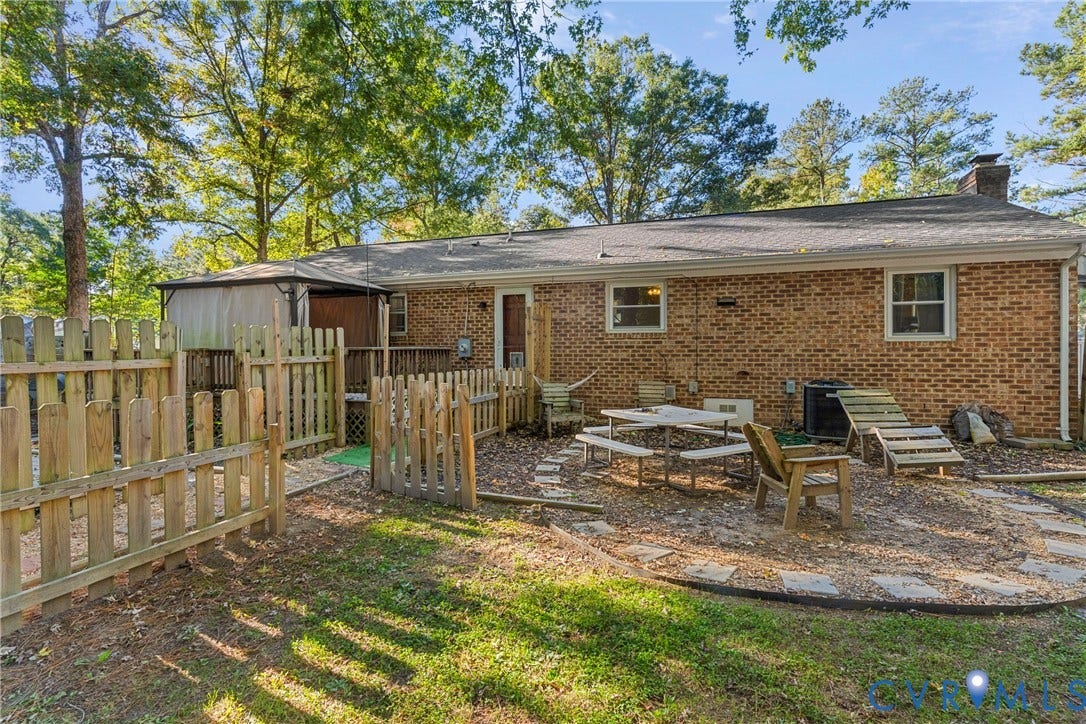 8444 New London Road, Mechanicsville, VA 23116 Exterior brick facade featuring a wood-style privacy fence, a wooden deck, and a multi-tiered outdoor hardscape area