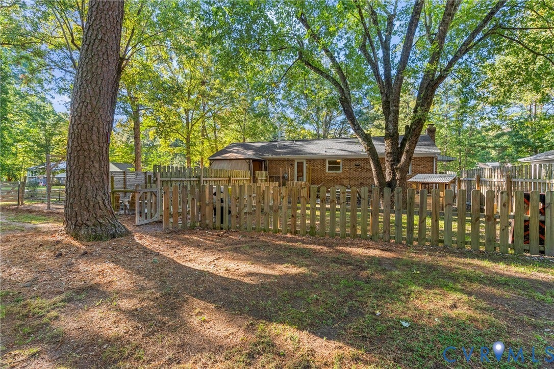 8444 New London Road, Mechanicsville, VA 23116 Brick exterior, wooden perimeter fencing, and mature trees on a level lot