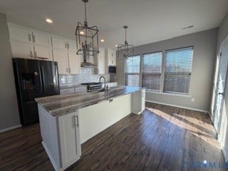 2144 Perennial Circle, Henrico, VA 23233 Kitchen featuring white shaker-style cabinetry, an oversized central island with stone-finish countertops, geometric metal pendant lighting, white subway tile backsplash, and wood-finish flooring