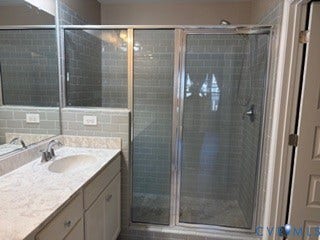 2144 Perennial Circle, Henrico, VA 23233 Bathroom featuring a stone-pattern vanity countertop, an undermount sink with a chrome faucet, and a walk-in shower enclosed by a framed glass door with subway-style tile wall surrounds