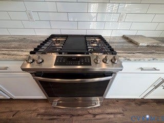 2144 Perennial Circle, Henrico, VA 23233 Stainless steel five-burner gas range with central griddle, light-toned stone-patterned countertops, white subway tile backsplash, and shaker-style cabinetry with satin nickel pulls