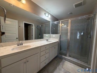 2144 Perennial Circle, Henrico, VA 23233 Dual-sink vanity with stone-finish countertop, full-width wall mirror, and walk-in shower with glass enclosure and subway tile surround
