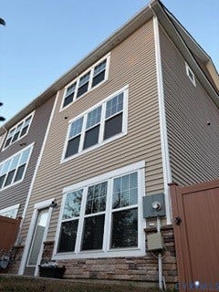 2144 Perennial Circle, Henrico, VA 23233 Multi-story exterior featuring tan horizontal siding, stacked stone veneer foundation, white trim detailing, and multiple double-pane windows