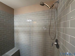 2144 Perennial Circle, Henrico, VA 23233 Shower enclosure featuring gray subway tile surround, built-in tiled bench, and adjustable handheld shower fixture with metallic finish