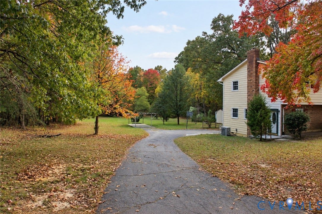 9711 Old Stage Road, Prince George, VA 23875 Two-story home with light-toned siding, exterior brick chimney, paved driveway, and expansive lawn featuring mature trees