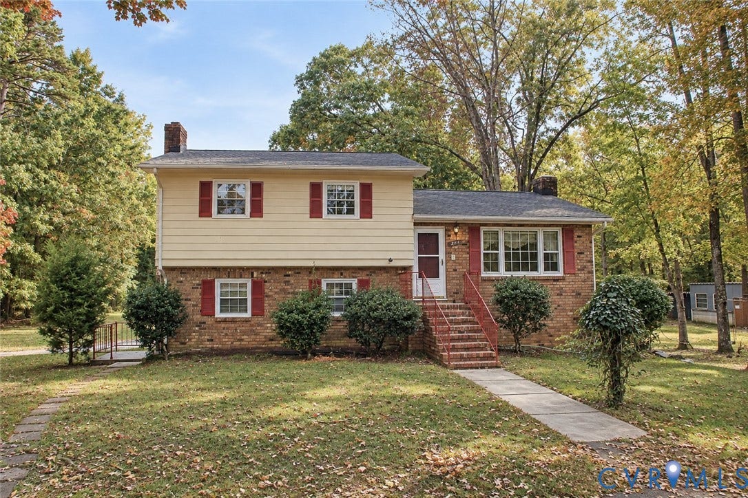 9711 Old Stage Road, Prince George, VA 23875 Split-level exterior featuring a brick and horizontal siding facade, red shutter accents, multi-pane windows, a brick-stepped entry, and a concrete walkway