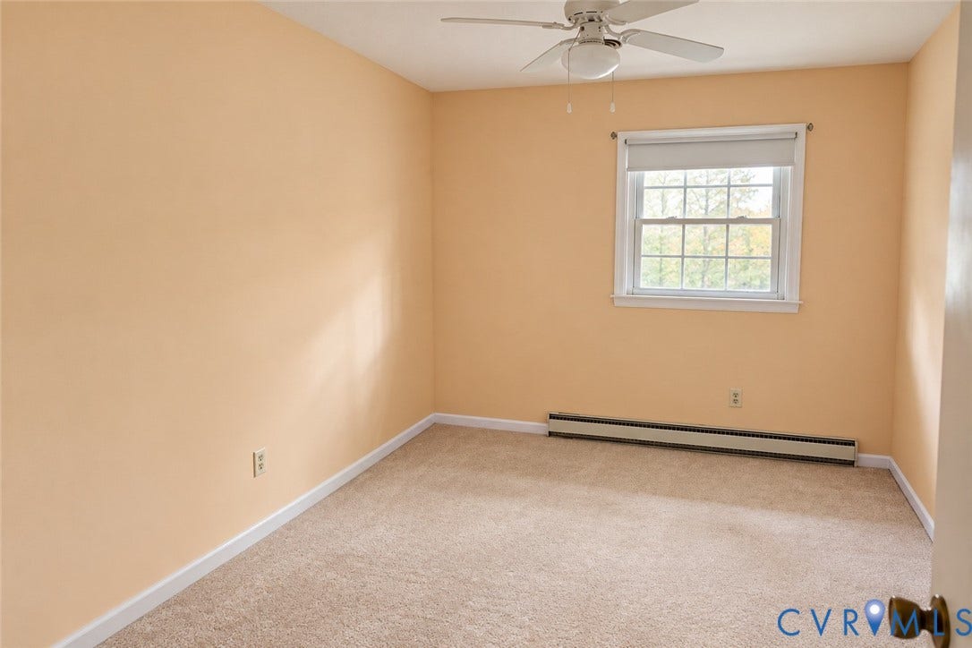 9711 Old Stage Road, Prince George, VA 23875 Room featuring neutral wall tones, wall-to-wall carpeting, a multi-pane window with a roller shade, and a ceiling-mounted fan with light fixture