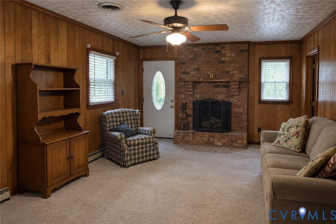 9711 Old Stage Road, Prince George, VA 23875 Wood-paneled walls, floor-to-ceiling brick fireplace with an integrated mantel, ceiling-mounted light fixture with fan, and solid-core entry door with an oval glass insert