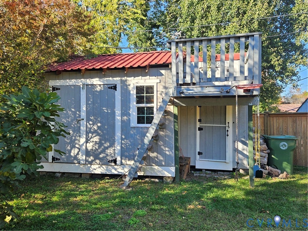 1206 Westminster Avenue, Richmond, VA 23227 Outbuilding with a red metal roof, vertical board-and-batten siding, double entry doors, single-hung window, and an attached elevated wooden deck with a ladder