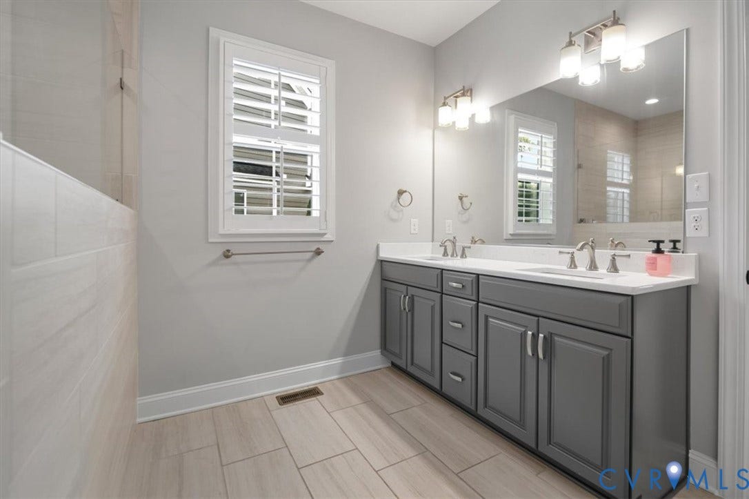12168 Readers Pointe Drive, Readers Branch, Goochland, VA 23103 Double vanity featuring a white surface, charcoal-grey shaker cabinetry, dual under-mount sinks, polished chrome fixtures, and a large wall-mounted mirror