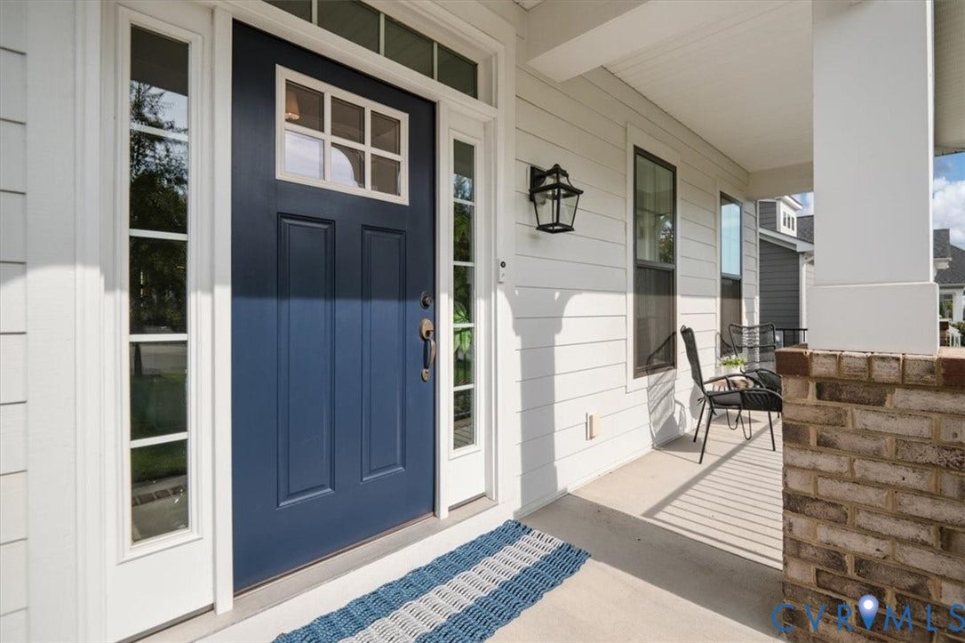 12168 Readers Pointe Drive, Readers Branch, Goochland, VA 23103 Covered entryway featuring a navy blue front door with a transom window, sidelights, exterior sconce lighting, and a brick-based support column