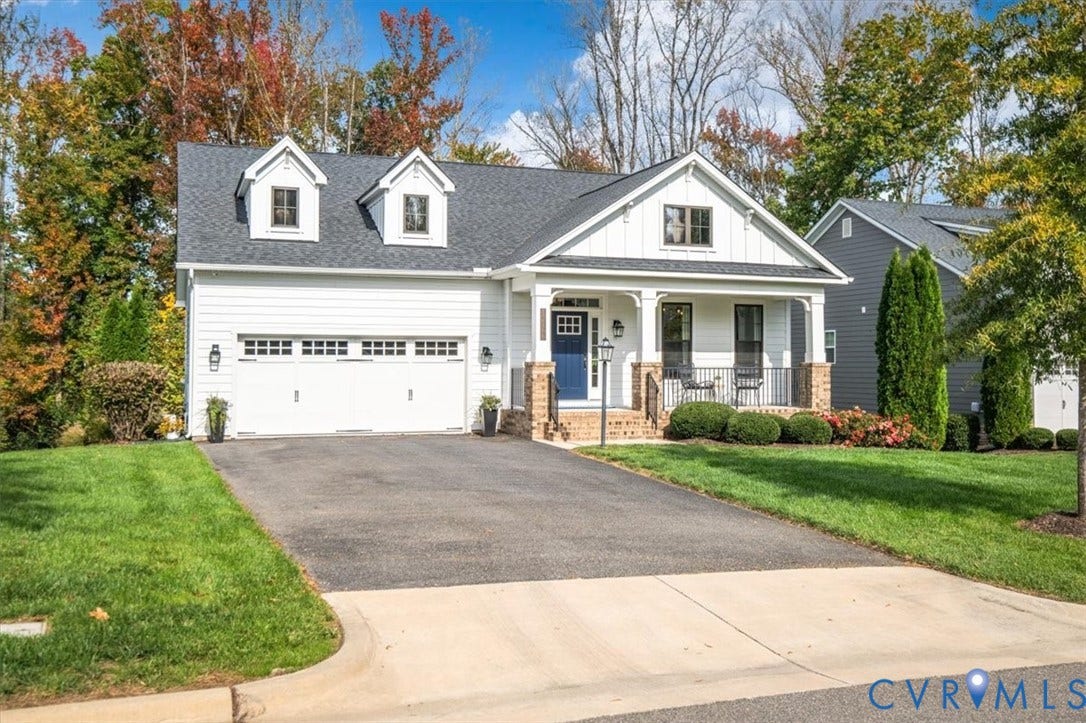 12168 Readers Pointe Drive, Readers Branch, Goochland, VA 23103 Two-story residence featuring white horizontal siding, a covered front porch with brick column bases, a two-car garage, and dual roof dormers