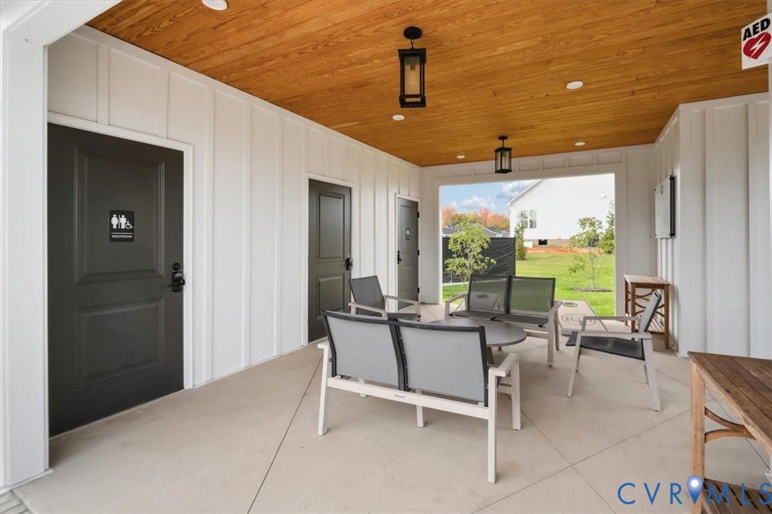 12168 Readers Pointe Drive, Readers Branch, Goochland, VA 23103 Covered patio featuring a wood-plank ceiling, board-and-batten siding, concrete flooring, and matte black pendant lighting