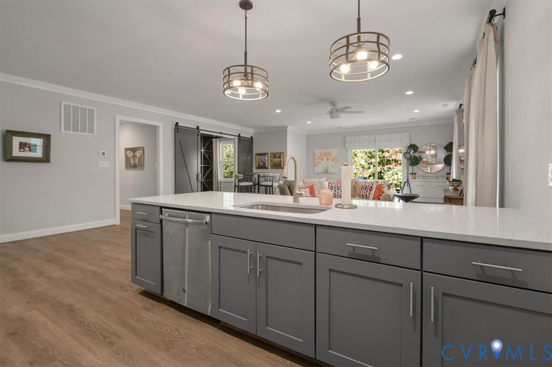 12168 Readers Pointe Drive, Readers Branch, Goochland, VA 23103 Terrace Level Kitchen island featuring a stone-composite countertop, undermount stainless steel sink, wood-finish cabinetry, and industrial-style pendant lighting, complemented by sliding barn-style doors