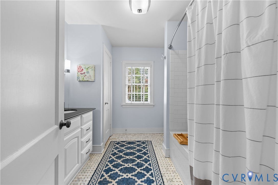 1203 Rothesay Circle, Windsor Farms, Richmond, VA 23221 Bathroom featuring white cabinetry with a dark countertop, subway tile shower surround, patterned tile flooring, and a multi-pane window