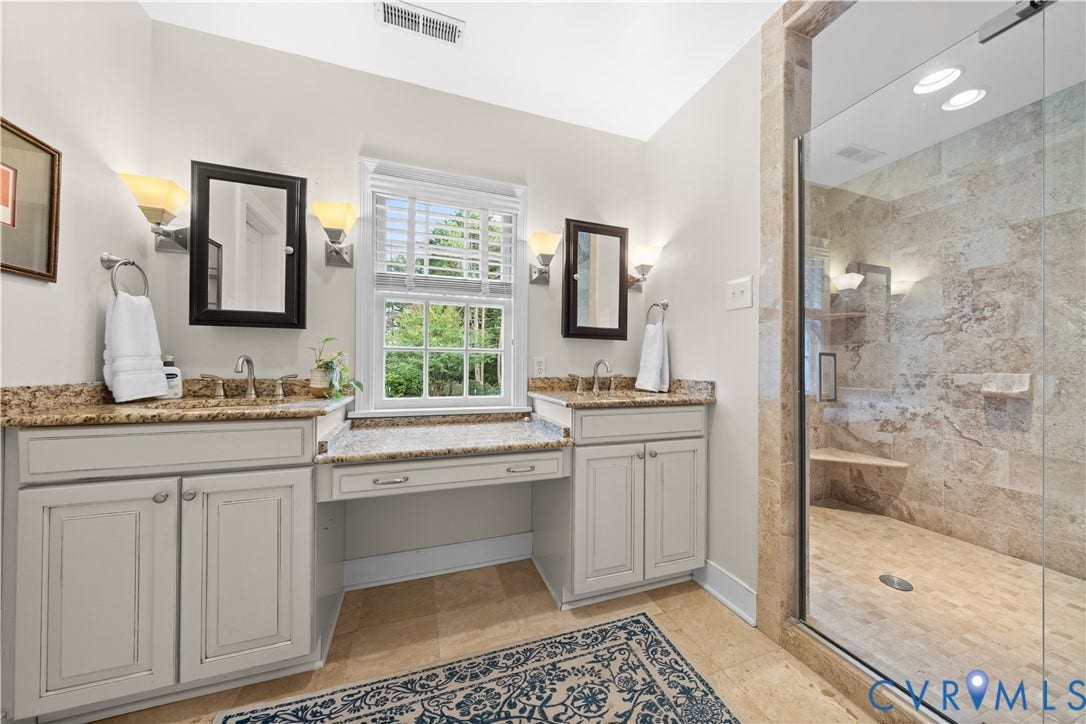 1203 Rothesay Circle, Windsor Farms, Richmond, VA 23221 Double vanity with stone countertop, central built-in vanity desk, wall-mounted sconce lighting, and walk-in shower with stone tile surround and integrated bench