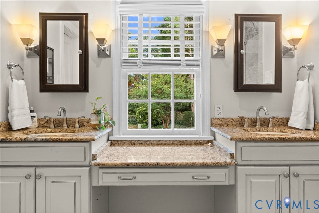 1203 Rothesay Circle, Windsor Farms, Richmond, VA 23221 Double vanity featuring stone countertops, integrated cabinetry, dual wall-mounted mirrors, sconce lighting, and a center sitting area