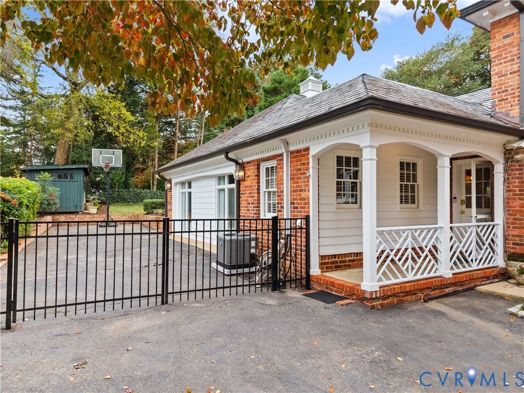 1203 Rothesay Circle, Windsor Farms, Richmond, VA 23221 Brick and horizontal siding exterior featuring a covered porch with decorative wood lattice railing, dentil molding, and asphalt driveway with integrated metal fencing