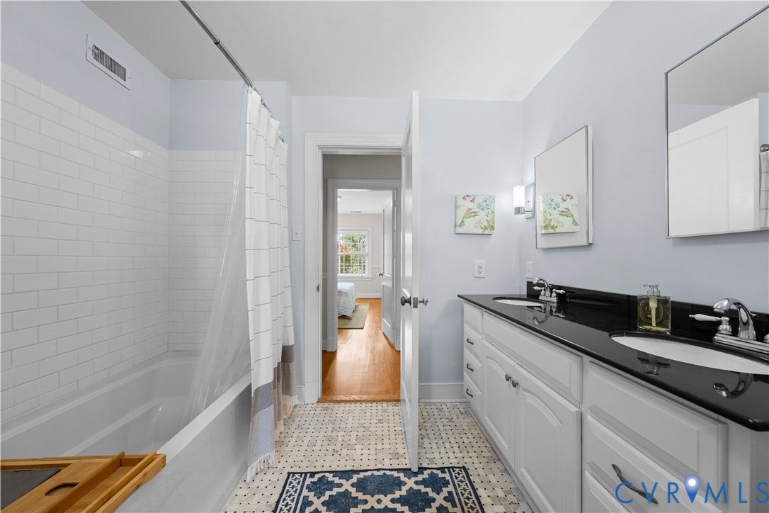 1203 Rothesay Circle, Windsor Farms, Richmond, VA 23221 Bathroom featuring a dual-sink vanity with a dark stone countertop, white cabinetry, subway tile bathtub surround, and geometric patterned floor tiling