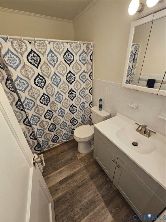 1112 E 15th Street, Richmond, VA 23224 Bathroom featuring wood-finish flooring, a vanity with a solid-surface countertop and integrated sink, a tiled tub surround, and a medicine cabinet with mirrored doors