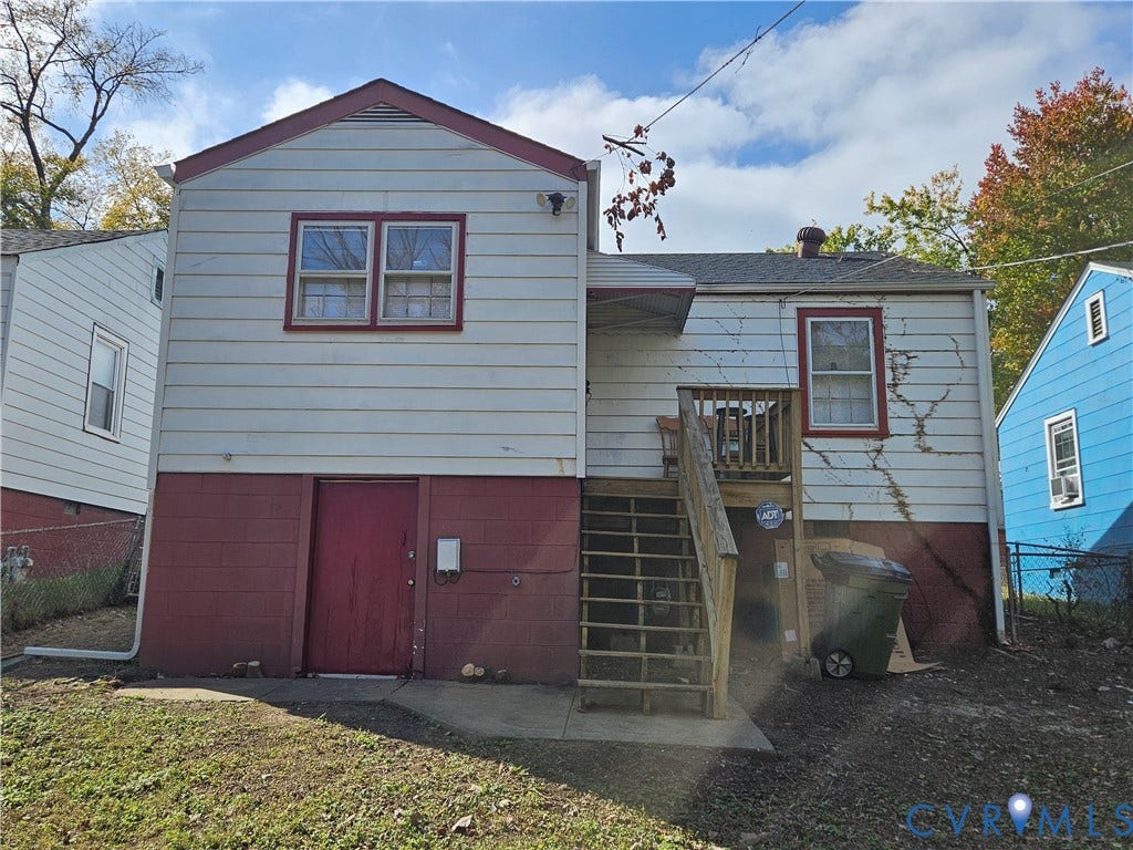 1112 E 15th Street, Richmond, VA 23224 Two-story exterior featuring light-toned horizontal siding, a masonry foundation, multi-pane windows, and a wooden staircase providing exterior access