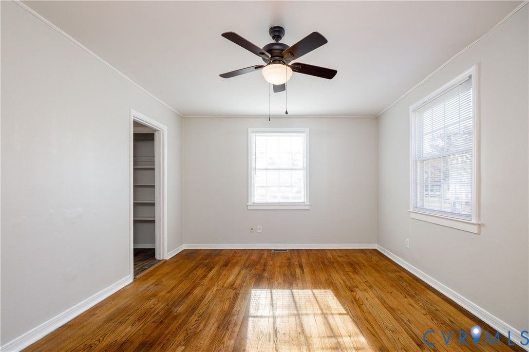 1010 E 17th Street, Oak Grove, Richmond, VA 23224 Room featuring wood-finish flooring, a ceiling fan with integrated lighting, two windows with white trim, and built-in shelving within a doorway