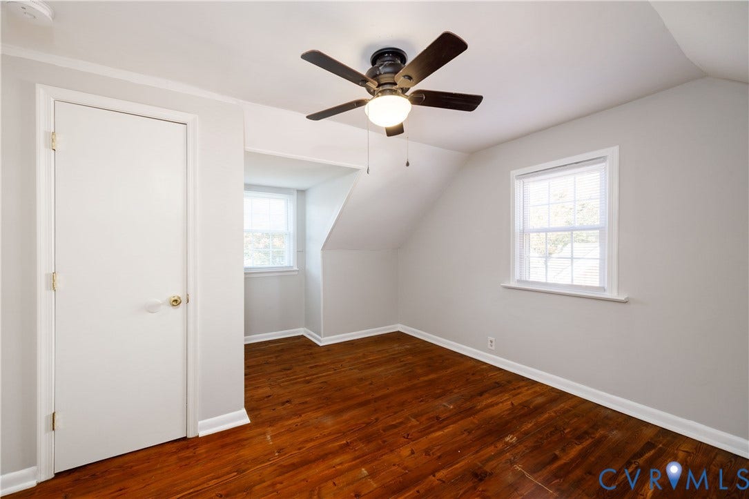 1010 E 17th Street, Oak Grove, Richmond, VA 23224 Interior room featuring dark wood-finish flooring, two multi-pane windows, a recessed dormer nook, and a ceiling fan with integrated lighting