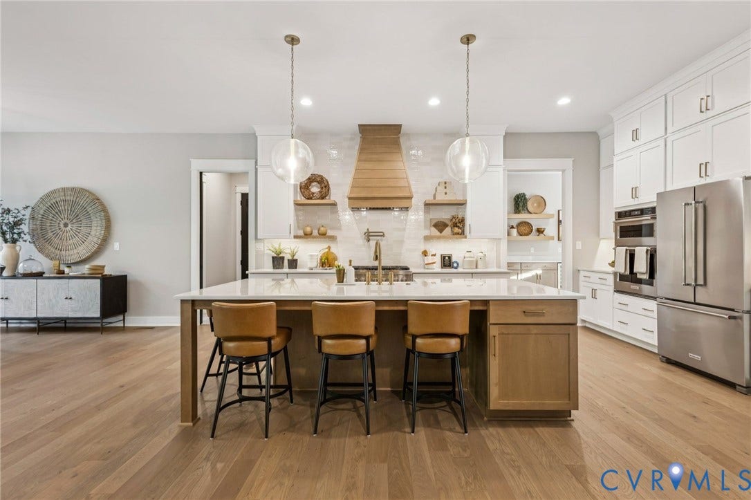 9275 Topeka Road, Quinton, VA 23141 Spacious kitchen featuring a large central island with seating, pendant lighting, wood-finish flooring, white cabinetry, and stainless steel appliances